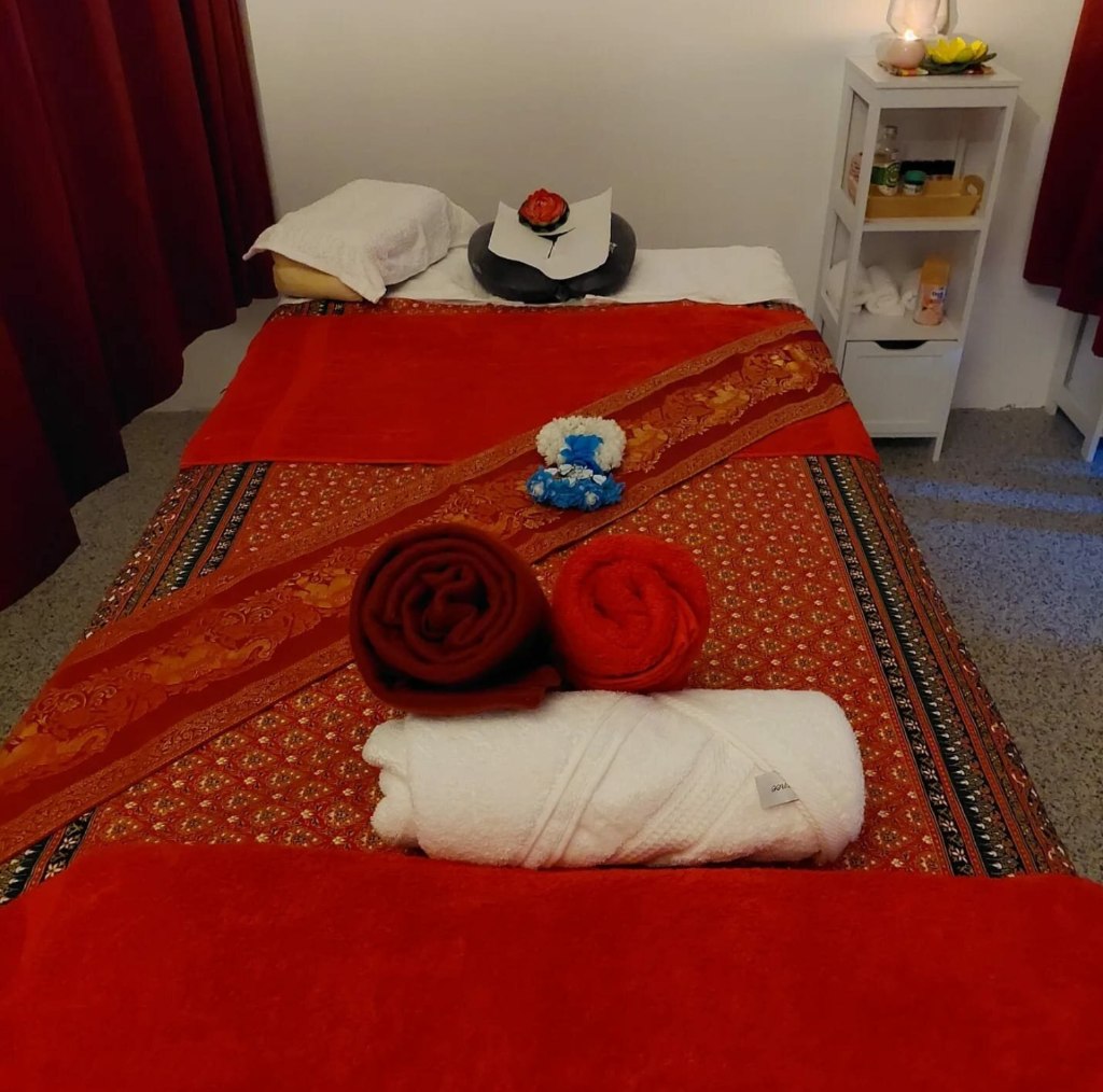 Traditionelle Massageliege mit roter Thai-Decke