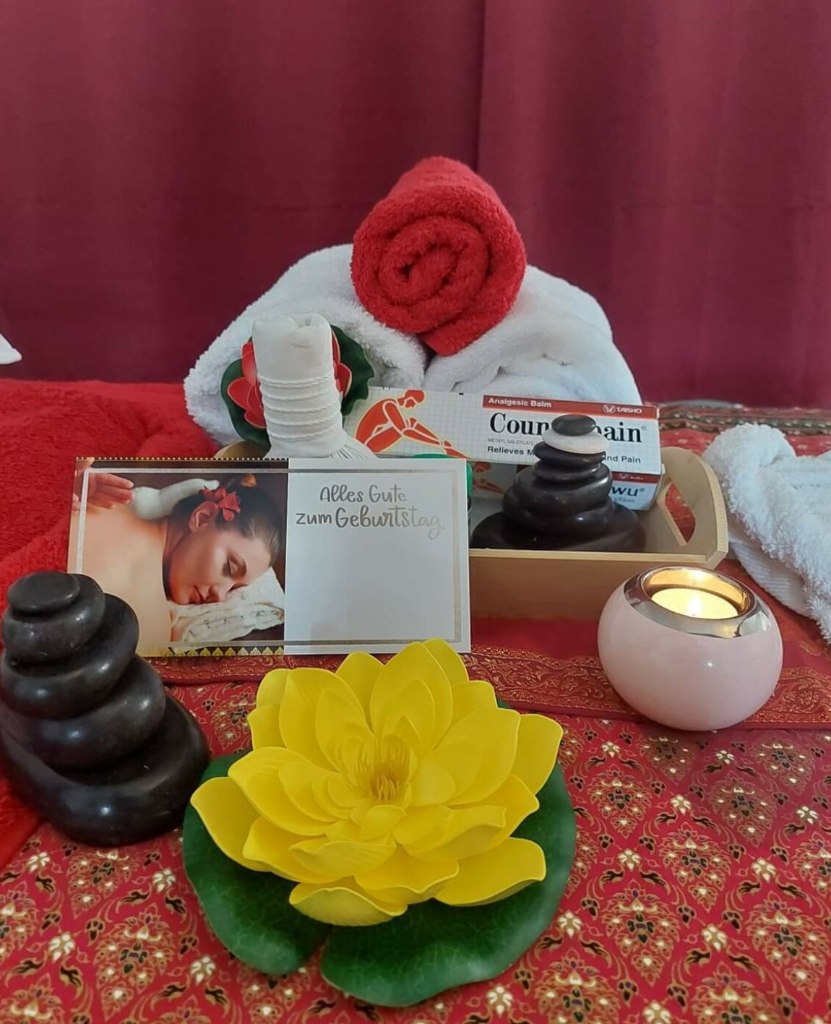 Spa-Arrangement mit Lotusblüte, Hot Stones und Kräuterstempel